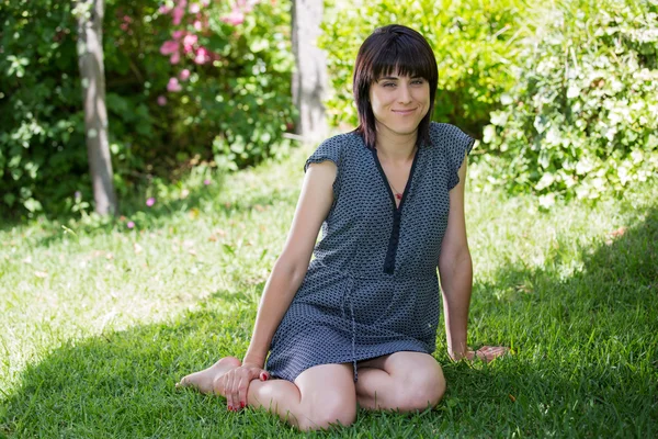 Femme posant assise, souriant à la caméra, à l'extérieur — Photo