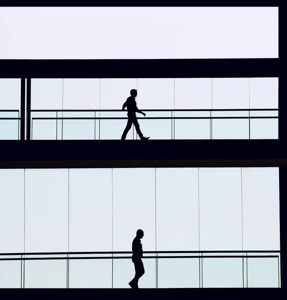 Silhouettenaufnahme zweier Geschäftsleute in einem modernen Bürogebäude — Stockfoto