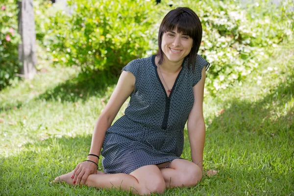 Femme décontractée posant assise, souriante, en plein air — Photo