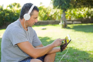 genç adam bir kulaklık ile müzik dinleme tablet pc ile rahatlatıcı