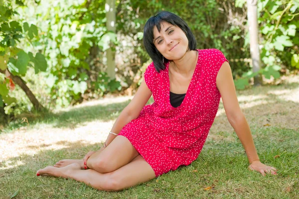 Casual woman posing seated, smiling at the camera, outdoors — Stock Photo, Image