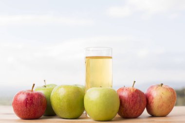 Elma ve elma suyu ahşap bir masada, açık havada.