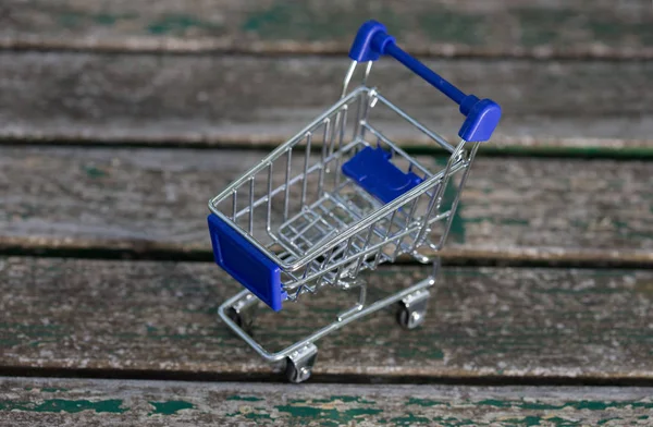 Carrinho de compras pequeno, em uma mesa de madeira — Fotografia de Stock