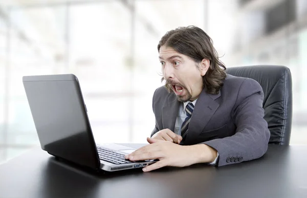 Jovem empresário surpreso trabalhando com é laptop no escritório — Fotografia de Stock