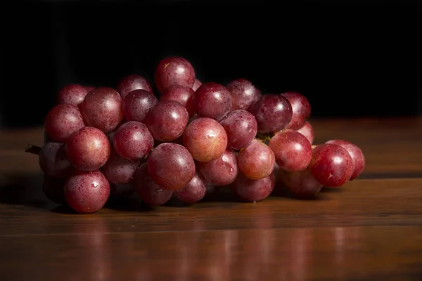 Eine Traube roter Trauben vor hölzernem Hintergrund — Stockfoto