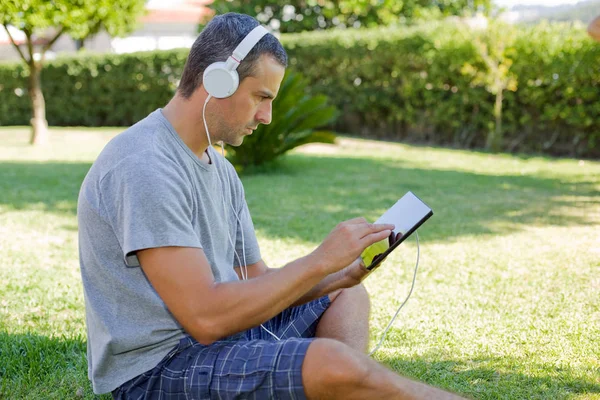 Giovane che si rilassa con un tablet pc ascoltando musica con le cuffie — Foto Stock