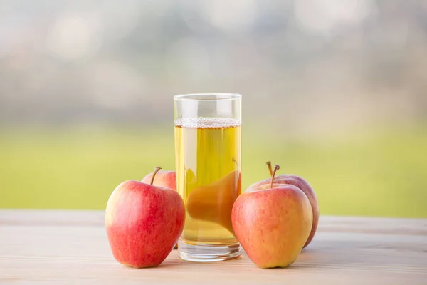 Äpfel und Apfelsaft auf einem Holztisch, im Freien — Stockfoto