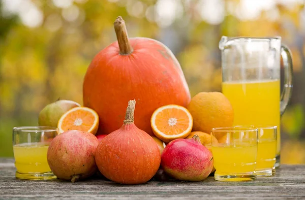 Saftgläser und jede Menge Herbstfrüchte auf Holztisch, draußen — Stockfoto