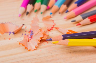 Ahşap masa üzerinde yontulmuş talaşlı ahşap renkli kalemler.