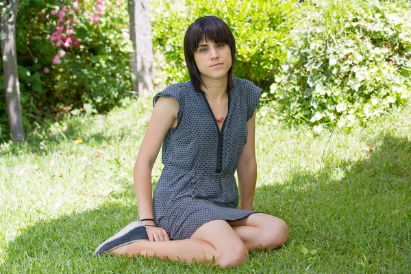 Mulher casual posando sentado, sorrindo para a câmera, ao ar livre — Fotografia de Stock