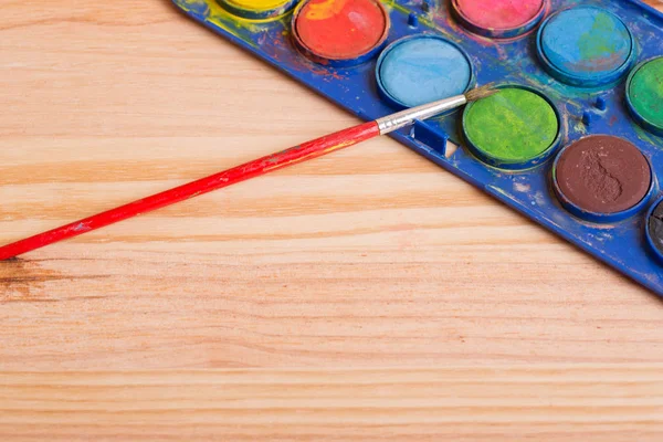 Ahşap arka planda boyalı kirli fırçalar.