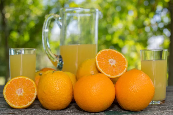 정원에 놓인 맛있는 오렌지 주스와 탁자 위의 오렌지 — 스톡 사진
