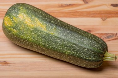 Sarı ahşap arka planda bir yeşil kabak sebzesi.