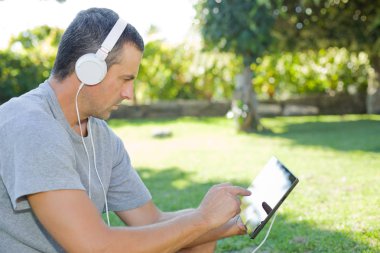 adam rahatlatıcı bir kulaklık ile müzik dinleme tablet pc ile