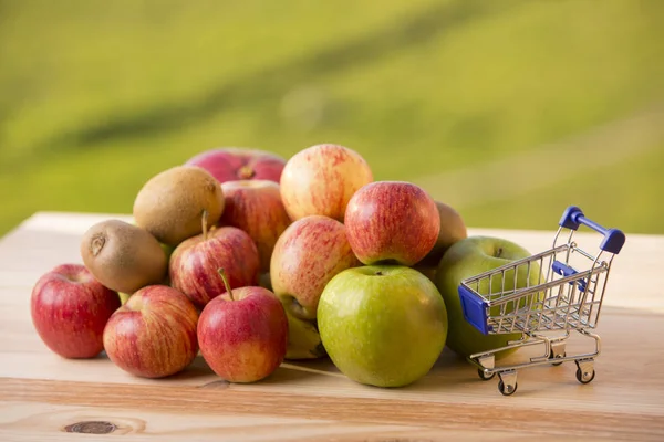 Variété de fruits et un panier sur une table en bois, en plein air — Photo