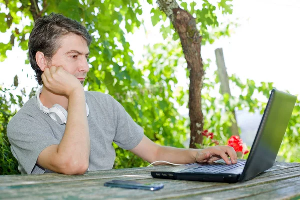 Człowiek siedzi odkryty pracy z laptopem — Zdjęcie stockowe