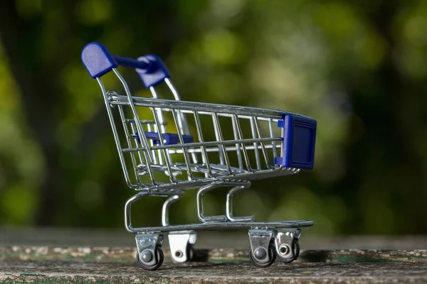 Carrinho de compras pequeno, quadro de estúdio em uma mesa de madeira — Fotografia de Stock