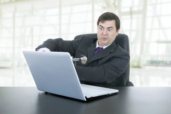 Бизнесмен с молотком, разбивающим ноутбук, в офисе — стоковое фото