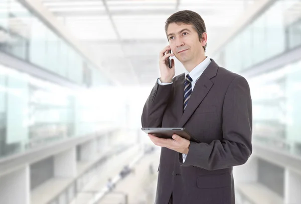 Businessman using touch pad of tablet pc, on the phone, at the office — Stock Photo, Image