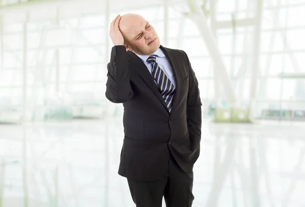 Επιχειρηματία σε ένα κοστούμι χειρονομίες με έναν πονοκέφαλο στο γραφείο — Φωτογραφία Αρχείου