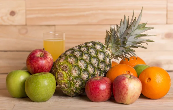 Mängd olika frukter och orange juice på ett träbord, studio bild — Stockfoto