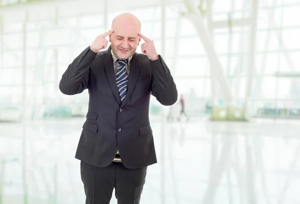 Üzletember öltönyös gesztusokban fejfájással, az irodában. — Stock Fotó
