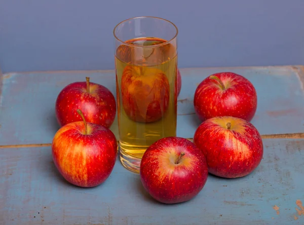Sok jabłkowy i czerwone jabłka na niebieskim tle stare drewniane — Zdjęcie stockowe