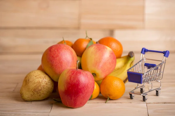 Frukt och en kundvagn på ett träbord, studio bild — Stockfoto