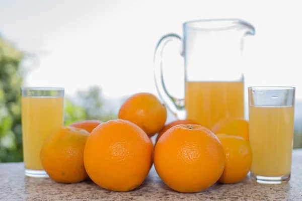 Délicieux jus d'orange et d'oranges sur la table dans le jardin — Photo