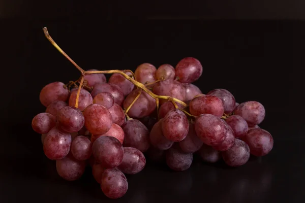 Um monte de uvas vermelhas sobre um fundo preto — Fotografia de Stock