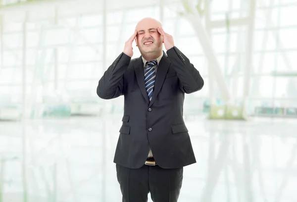 Takım elbiseli bir işadamı ofisinde baş ağrısıyla el kol hareketi yapar. — Stok fotoğraf