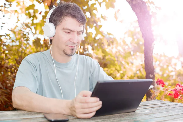 Uomo che lavora con un tablet pc, con cuffie, esterno — Foto Stock