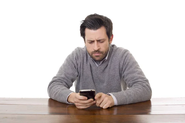 Hombre casual preocupado con un teléfono, en un escritorio, aislado —  Fotos de Stock