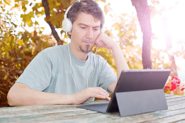 Uomo che lavora con un tablet pc, con cuffie, esterno — Foto Stock