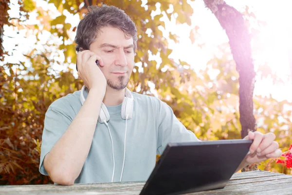 Casual man working with a tablet pc, with headphones, outdoor — Stock Photo, Image