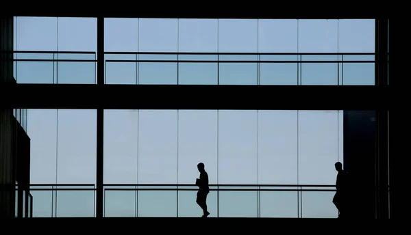 İki kişi bir modern ofis binası iç görünümünü siluet — Stok fotoğraf