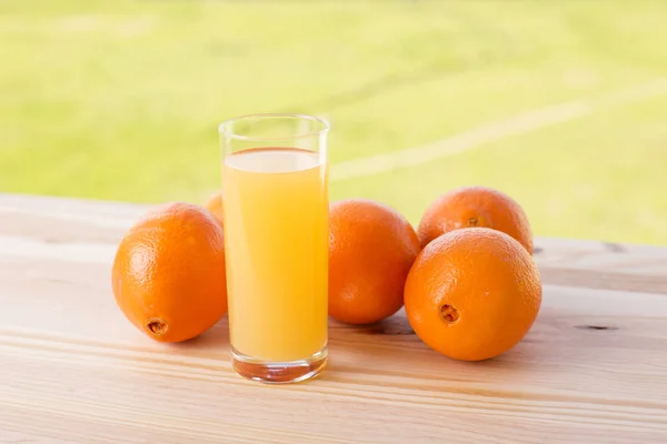 Verre de délicieux jus d'orange et d'oranges sur la table dans le jardin — Photo