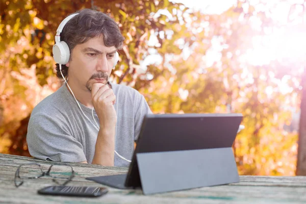 Casual uomo che lavora con un tablet pc, con cuffie, outdoor — Foto Stock