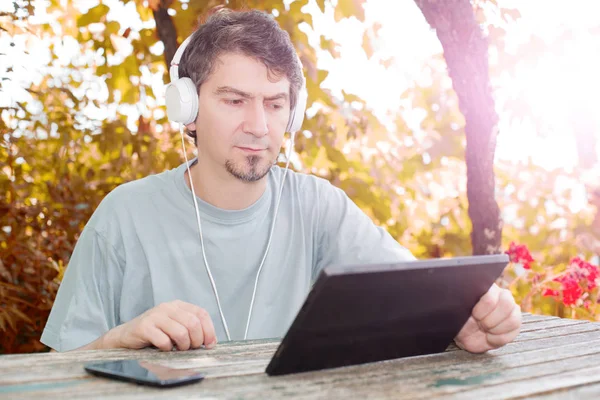 Homme travaillant avec une tablette pc, avec écouteurs, extérieur — Photo