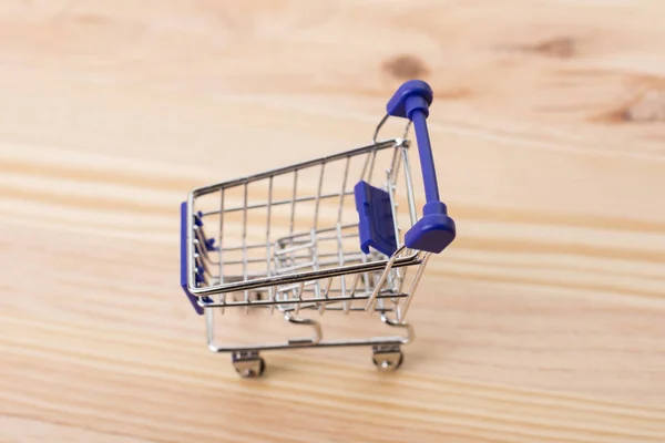 Carrinho de compras pequeno, quadro de estúdio em uma mesa de madeira — Fotografia de Stock