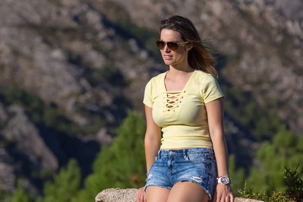 Молода щаслива жінка сидить на скелястій горі — стокове фото