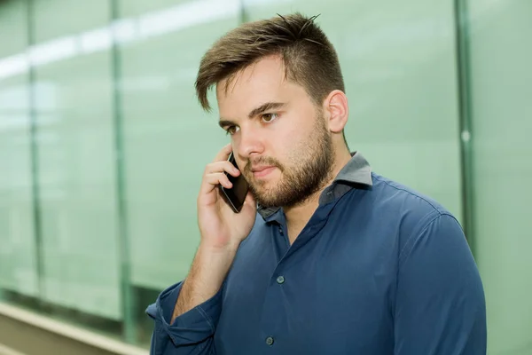 Fiatal alkalmi férfi a telefonban egy irodaházban — Stock Fotó