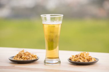 Soğuk bira, kavrulmuş fıstık, ahşap masa, açık hava.