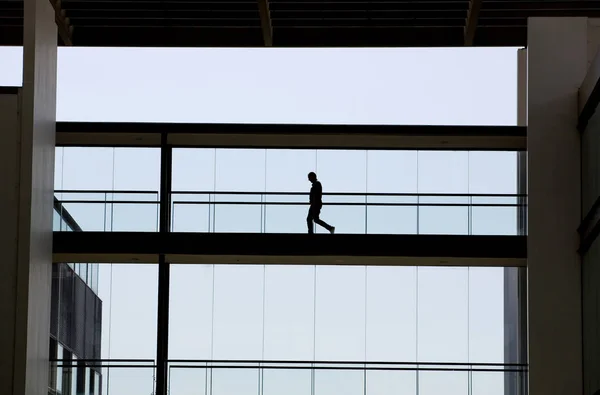 Vista silhueta de um jovem empresário num moderno edifício de escritórios interior — Fotografia de Stock
