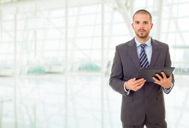 Ofiste elinde tablet olan genç bir işadamı var.