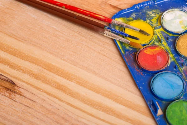 Ahşap arka planda boyalı kirli fırçalar.