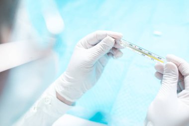 Çin gribinin ana belirtileri. Vücut ısısı yükselmiş. Doktor hastanın vücut ısısını ölçer..