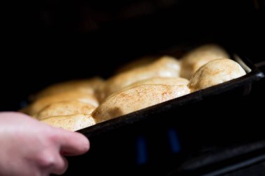 Aşçı pişirmek için fırına çörek koyar.