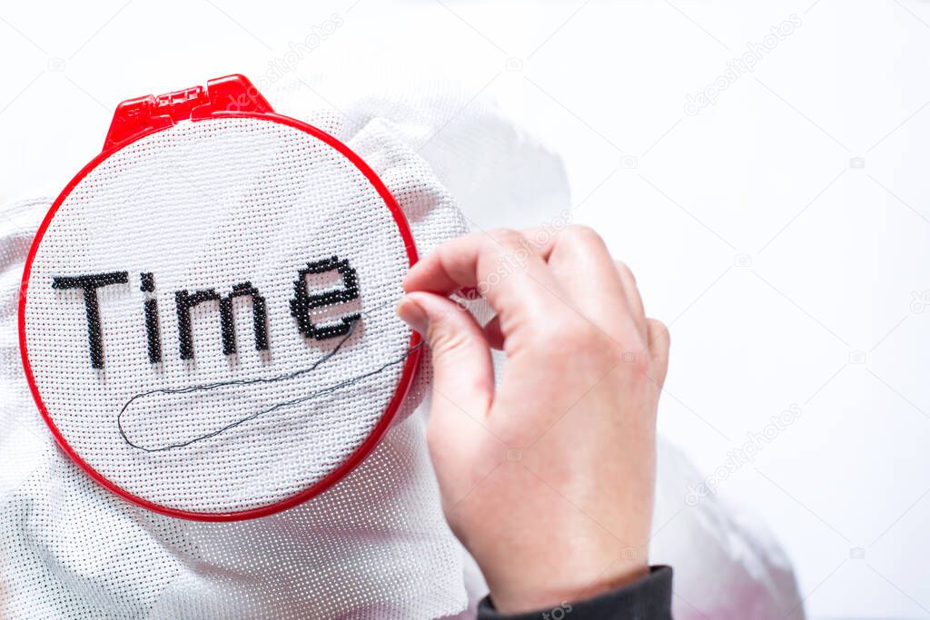 hands embroider the word beads, time on a white background. The concept of the word, time and time spending for your favorite pastime.
