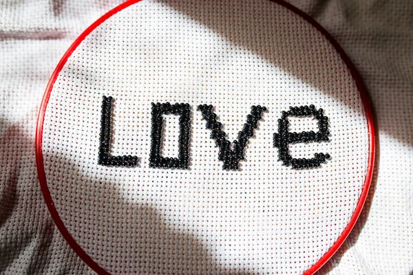 True love is tested by time. Beaded word, love. Black letters on a white background.